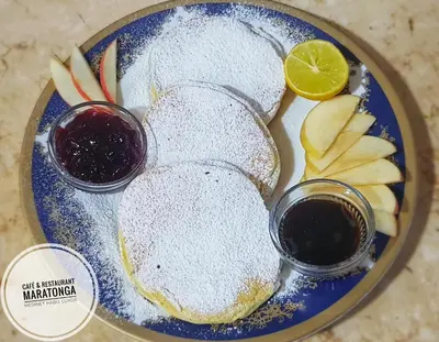 a blue plate with powdered sugar and fruit on it at HabuHeritageHomeStayInLuxor in Al Aqālitah