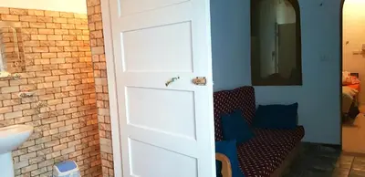 a door to a bathroom with a couch and a sink at HabuHeritageHomeStayInLuxor in Al Aqālitah