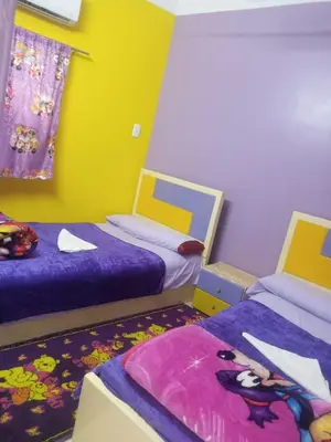 two beds in a room with yellow and purple at Fekry home in Aswan