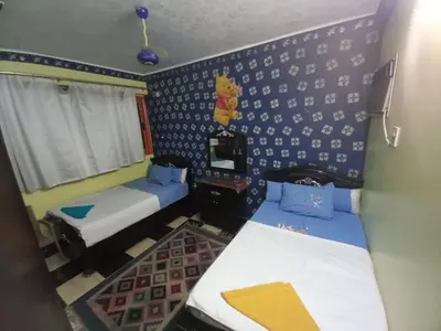 a room with two beds and a wall with blue and white wallpaper at Sabrina home in Aswan