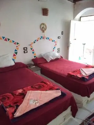 a bedroom with two beds with red sheets at hooly nubian in Aswan