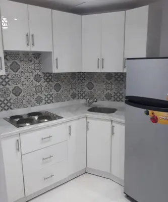 a kitchen with white cabinets and a refrigerator at Tawaya sahl hashesh in Hurghada