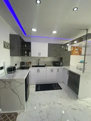 a kitchen with white cabinets and a purple lighting at Blue Whale Hurghada Beach Front Apartments City Centre in Hurghada