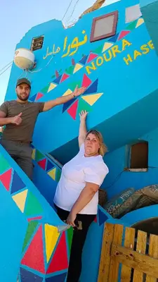 a man and a woman standing in front of a blue wall at Noura hasel nubian house in Aswan