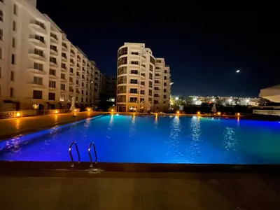 a large blue swimming pool at night with buildings at شقة علي البحر 2 in Hurghada