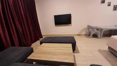 a living room with a red curtain and a tv at Aldau Heights Cozy big studio in Hurghada