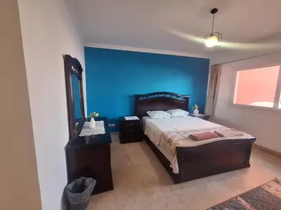 a bedroom with a bed and a blue wall at new marina . your best choice for family in Hurghada