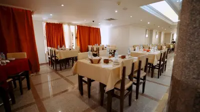 a restaurant with white tables and chairs and red curtains at New Sunset Resort in Aswan