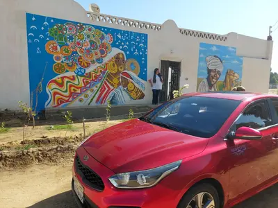 a red car parked in front of a mural at Mostafa Nubian Guesthouse in Najâ€˜ al MadÄbb