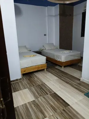 two beds in a room with wood floors at Cattleya Guesthouse in Aswan
