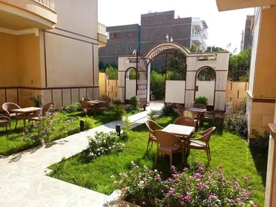 an outdoor patio with tables and chairs and flowers at Mikhaila Guest House in Luxor