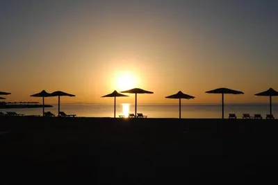 a group of umbrellas on the beach at sunset at Cecelia resort in Hurghada