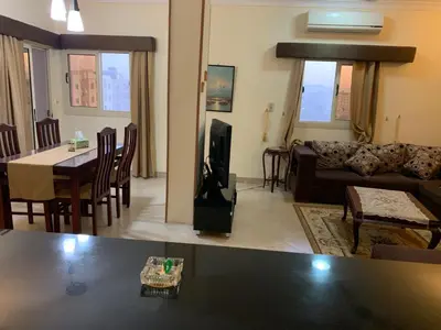 a living room with a couch and a table and a tv at شقة سكنية ذات طابع عائلى متميز بها كافة الامكانيات من فلتر ماء وواى فاى in Hurghada