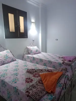a bedroom with two beds and a mirror on the wall at Nubian Queen Guest House in Aswan