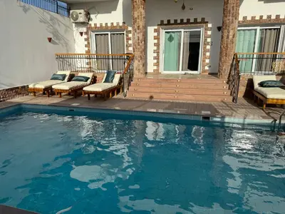 a swimming pool with two chairs and a house at Twilight palace in Luxor