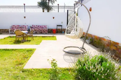 a garden with a swing and a table and chairs at Twilight palace in Luxor