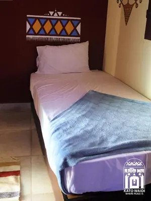 a bed with a blue blanket on top of it at Kato Waidi Nubian Resort in Aswan