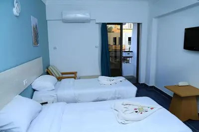 a hotel room with three beds and a television at Lamera Hotel in Hurghada