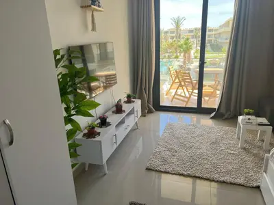 a living room with a white dresser and a large window at Cozy studio in G cribs in Hurghada