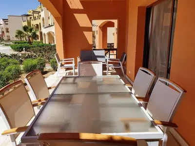a long table and chairs on a balcony at Brand New Waterfront Sabina Ground Floor Home in Hurghada