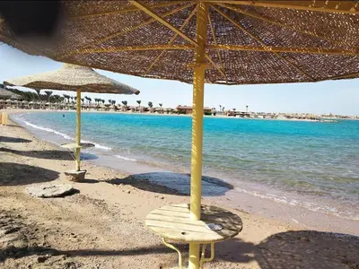 two straw umbrellas and a chair on a beach at Makadi heights luxury complex in Hurghada