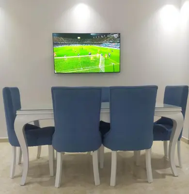 a table with blue chairs and a tv on a wall at Red Sea Panorama in Hurghada