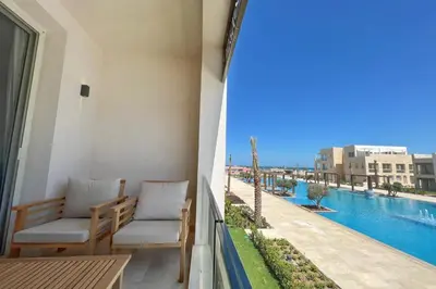 a balcony with two chairs and a view of the water at Modern & Mellow 1 BDR Mangroovy Free Beach & Pool Access in Hurghada