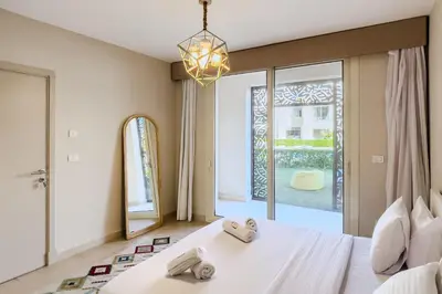 a bedroom with a white bed and a large window at Roomy & Relaxed 1BDR Mangroovy Free Beach & Pool in Hurghada