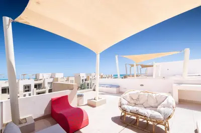 a balcony with a couch and a chair on a roof at Seascape 1 BDR Mangroovy Pool & Sea View in Hurghada