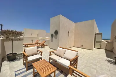 a patio with chairs and tables on a roof at Radiant & Ravishing 2 BDR Mangroovy Free Beach & Pool Access in Hurghada