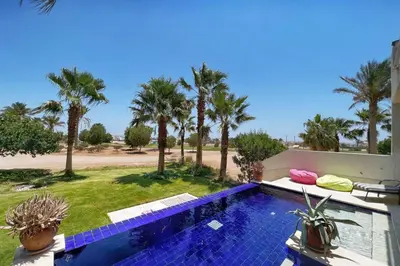 a swimming pool with palm trees in the background at Meditative & Blissful 2 BDR Villa Ancient Sands Private Pool in Hurghada