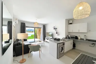 a kitchen and living room with a stove and a table at Lagoonfront Easy 1BDR Swan Lake El Gouna in Hurghada