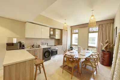 a kitchen with a table and chairs in a kitchen at Dazzling 2 BDR w Rooftop Mangroovy Free Pool & Beach Access in Hurghada