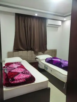two beds in a small room with a window at B in Hurghada