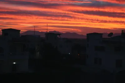 a sunset over a city with buildings and mountains at A Beautiful, Family-owned Penthouse Apartment, Overlooking the Red Sea Hurghada in Hurghada