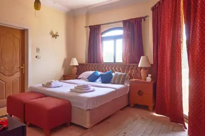 a bedroom with a bed with red curtains and a window at Sweet Rooms in Luxor