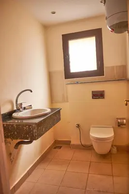 a bathroom with a toilet and a sink and a window at Sweet Rooms in Luxor