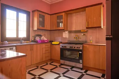 a kitchen with wooden cabinets and a stove top oven at Sweet Rooms in Luxor