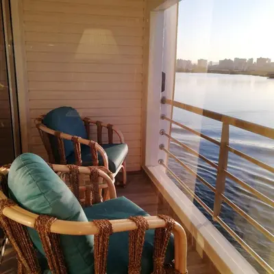 two rocking chairs on a porch with a view of the water at Nile Cruise 3 nights From Aswan to Luxor Every Friday, Monday and Wednesday with tours in Jazīrat al ‘Awwāmīyah