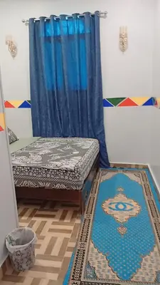 a room with a bed and a blue curtain at Kayan Guest House in Aswan