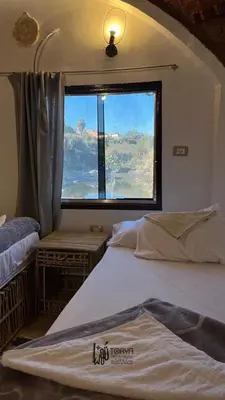 a bedroom with two beds and a large window at Torya Nubian House in Aswan
