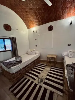 a room with two beds and a rug at Torya Nubian House in Aswan