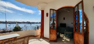 a house with a balcony with a view of the water at Nile View Panoramique and Garden West bank in Luxor