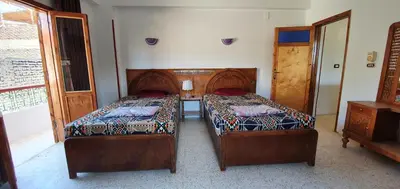 a bedroom with two beds and a window and a dresser at Nile View Panoramique and Garden West bank in Luxor