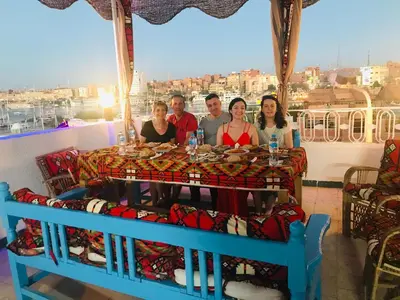 a group of people sitting around a table on a balcony at Gamal Robob Nubian Guest House in Aswan