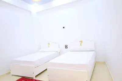 two white beds in a room with white walls at Tomorrow Land villa in Luxor