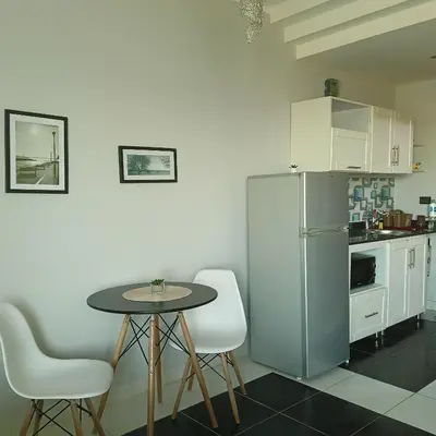 a small kitchen with a table and a refrigerator at Tony's Privy Beds by Red Sea in Hurghada