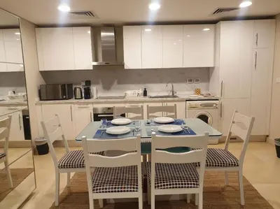 a kitchen with a table and chairs in a kitchen at Mangroovy - 1BR GF +2 wall beds Garden & Pool view in Hurghada