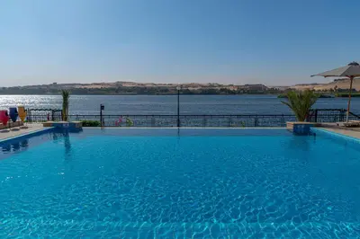 a large swimming pool next to a large body of water at Sonesta Nouba Hotel Aswan in Aswan
