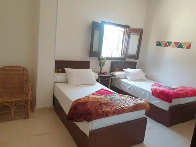 a bedroom with two beds and a window at النبلاء جيست هاوس نوبيان اسوان in Aswan